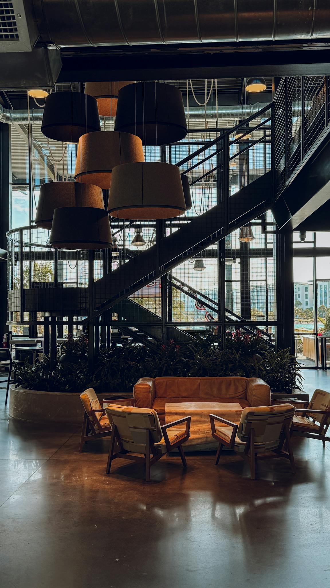 Contemporary lounge in an industrial setting featuring stylish lighting and cozy seating.