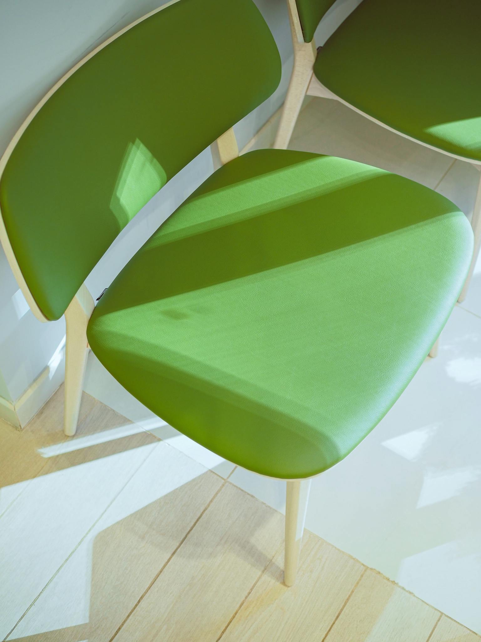 Minimalist green chairs design with natural sunlight indoors.