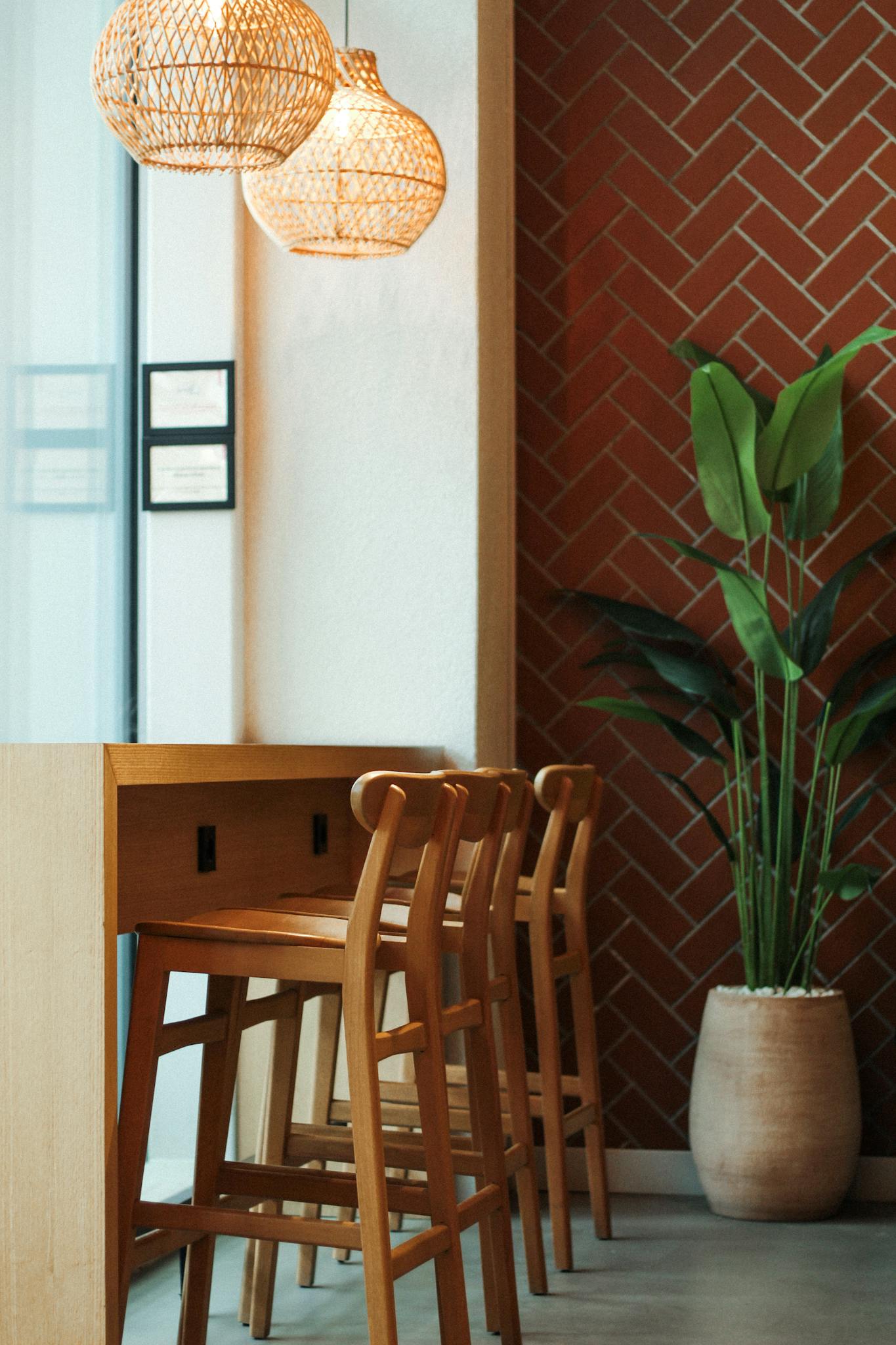 Stylish café interior featuring wooden chairs, woven lamps, and vibrant plant.